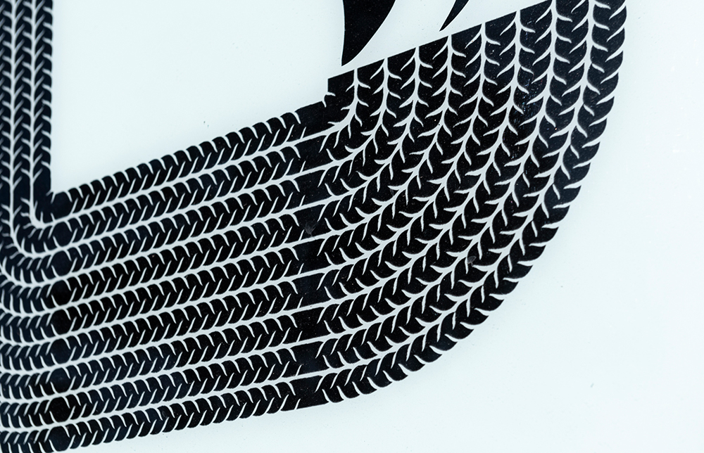 Detail of the artwork in the windows showing the braid and cornrow motif in black vinyl on a white surface.
